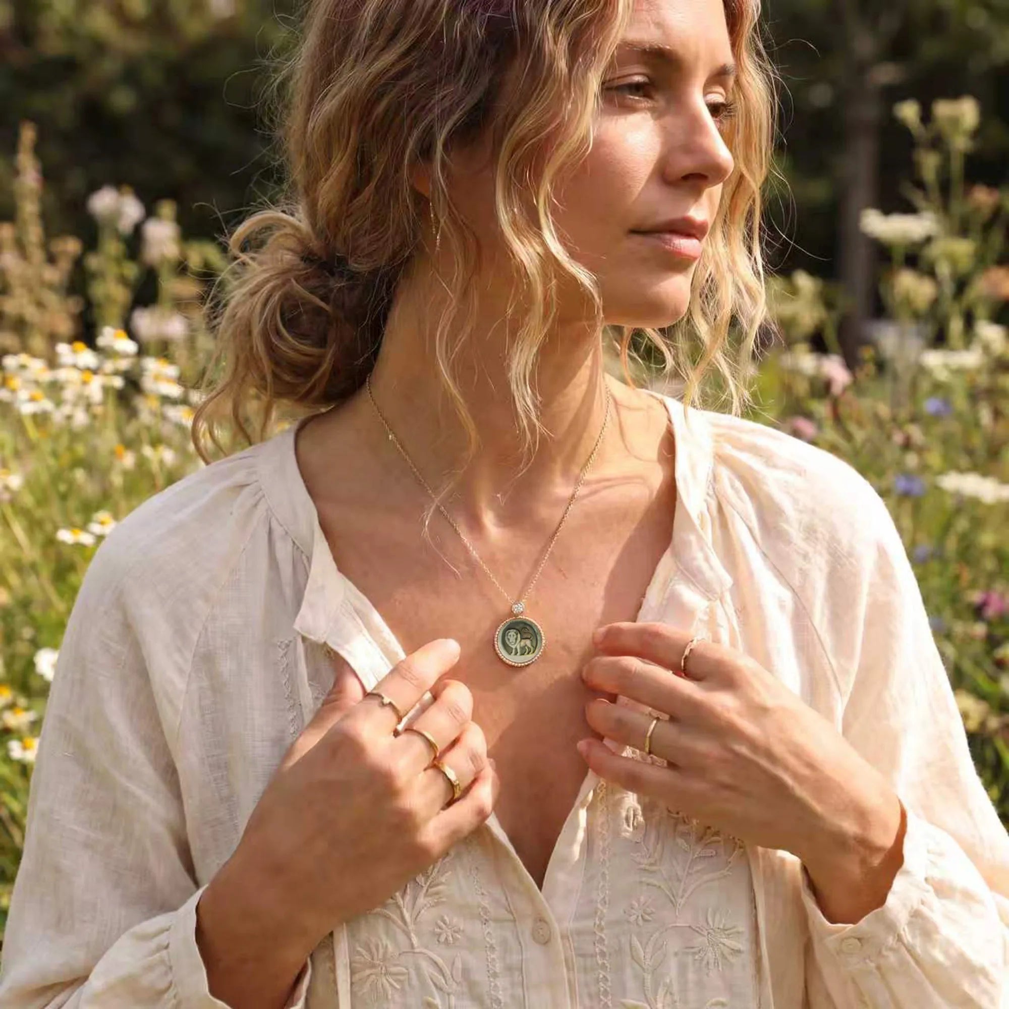 Blonde woman relaxing on a garden hammock admiring an abstract zodiac mother-of-pearl necklace with sculptural celestial carving by OceanCarvingLab.
