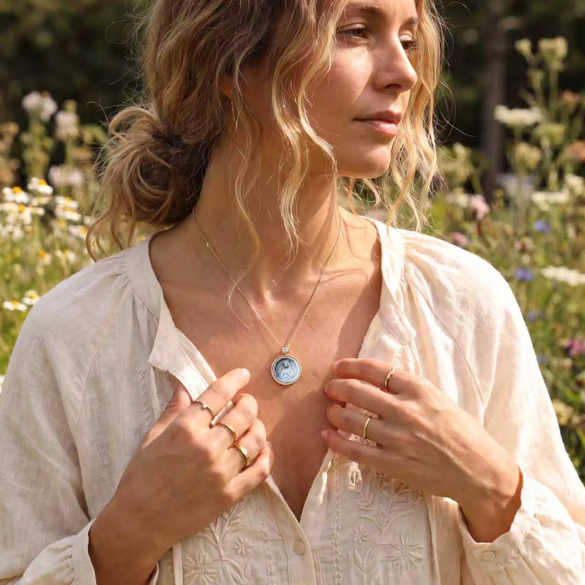 Elegant blonde woman amid countryside wildflowers wearing a Van Gogh style carved  Virgo  zodiac mother‑of‑pearl pendant necklace in gold plated sterling silver by OceanCarvingLab.